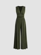 Woman gracefully posing in a navy wide-leg jumpsuit, highlighting the floor-length hem and flowing silhouette.