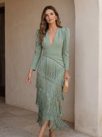 Back view of the long-sleeve green dress, emphasizing the elegant fall of the fabric and fringe.